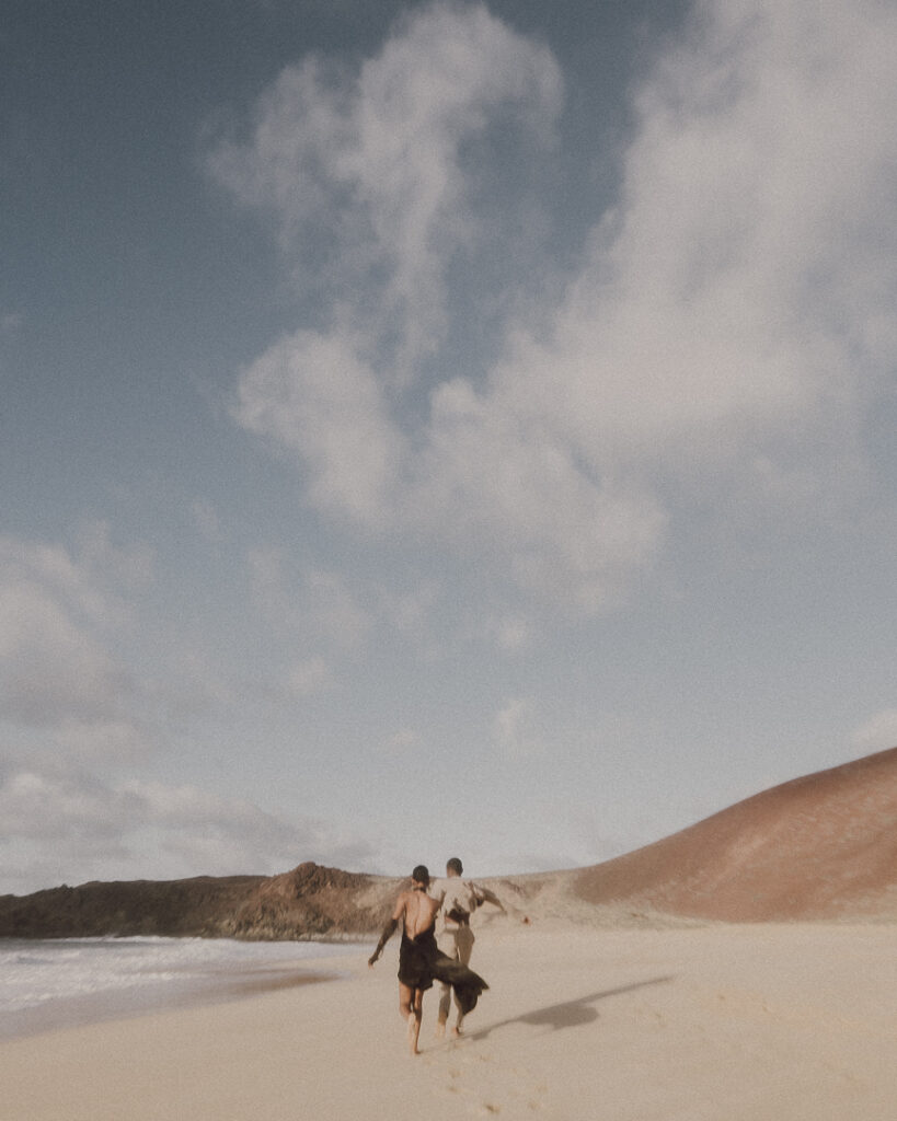 Couple run along one of the beautiful beach of Las Conchas. 