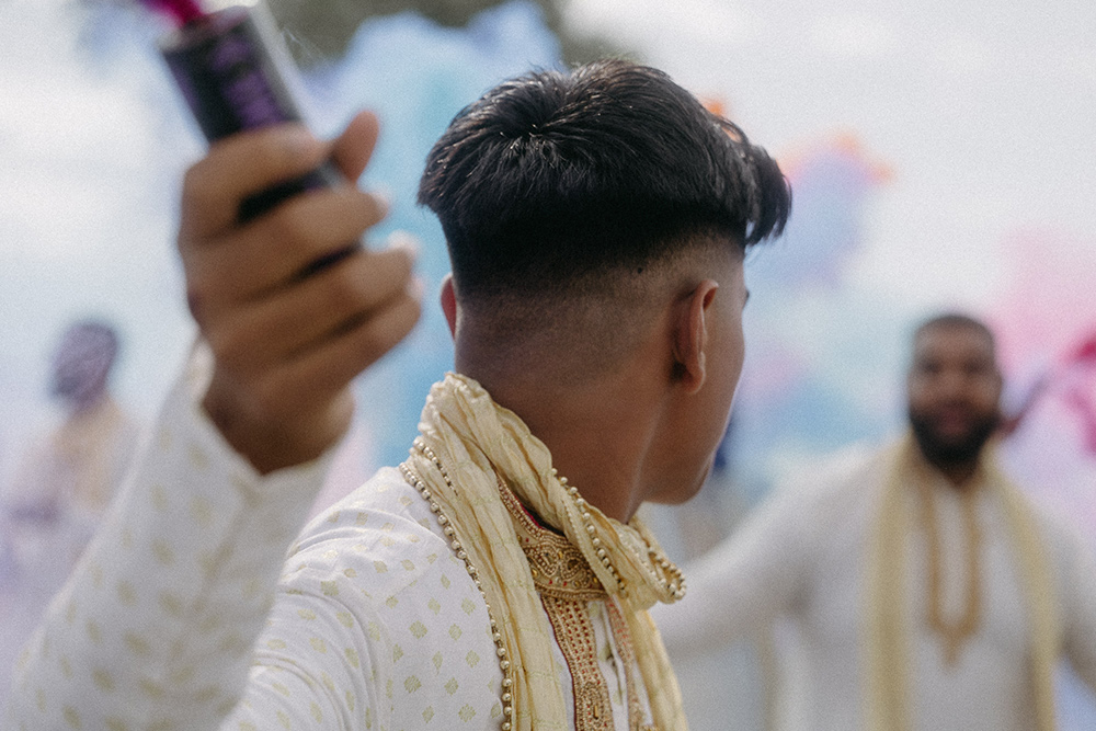 Young man holds smoke bomb during traditional Indian wedding ceremony