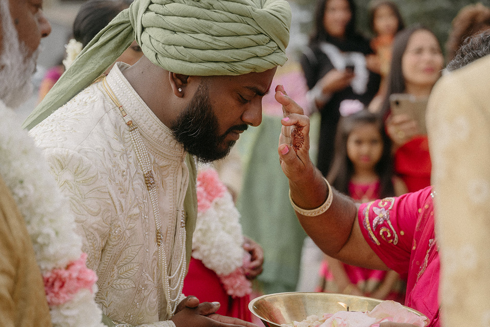 Priest applies bindi of kumkum powder to groom's forehead