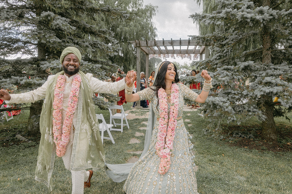 Bride and groom in traditional Indian wedding attire cheer after they are married
