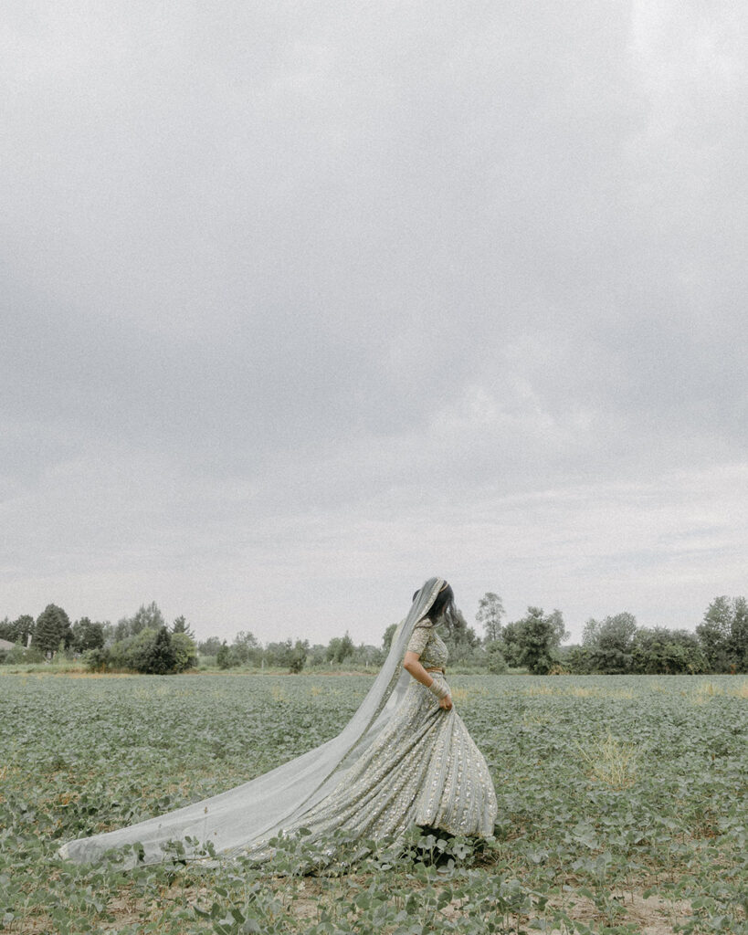Bride walks in traditional Indian wedding dress through a field